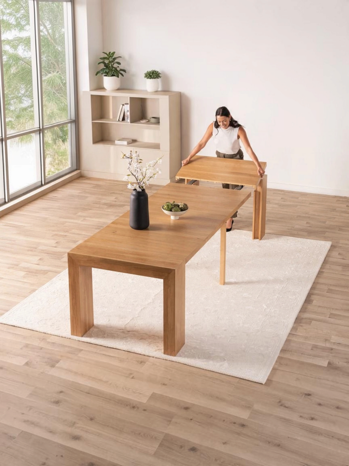Femme installant un panneau sur la table à manger extensible en chêne massif TOCO Meubles dans une pièce lumineuse