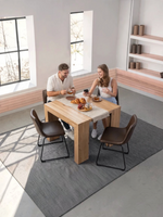Couple attablé à une table à manger extensible en bois massif TOCO Meubles dans un intérieur lumineux et moderne.