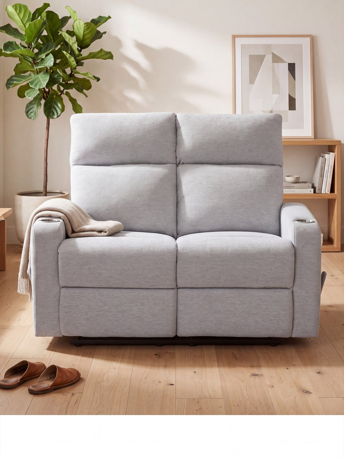 Causeuse inclinable Maxima de TOCO Meubles en tissu gris clair, compacte avec porte-gobelets dans un salon moderne.