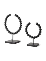 Deux objets décoratifs Tulane TOCO Meubles en forme de sphères brisées avec perles noires mates sur socles carrés.