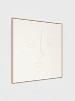 Cadre décoratif Dream I de TOCO Meubles avec un dessin au trait minimaliste d'un visage sur fond beige clair
