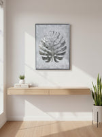 Cadre décoratif Paradise Palm II de TOCO Meubles avec motif de feuille tropicale argentée sur fond gris texturé.