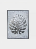Cadre décoratif TOCO Meubles Paradise Palm II avec une feuille de palmier argentée texturée sur fond gris clair