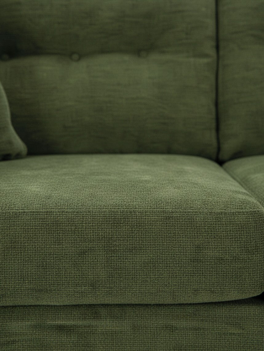 Gros plan sur le canapé Bixo de TOCO Meubles en tissu texturé vert olive avec détails capitonnés
