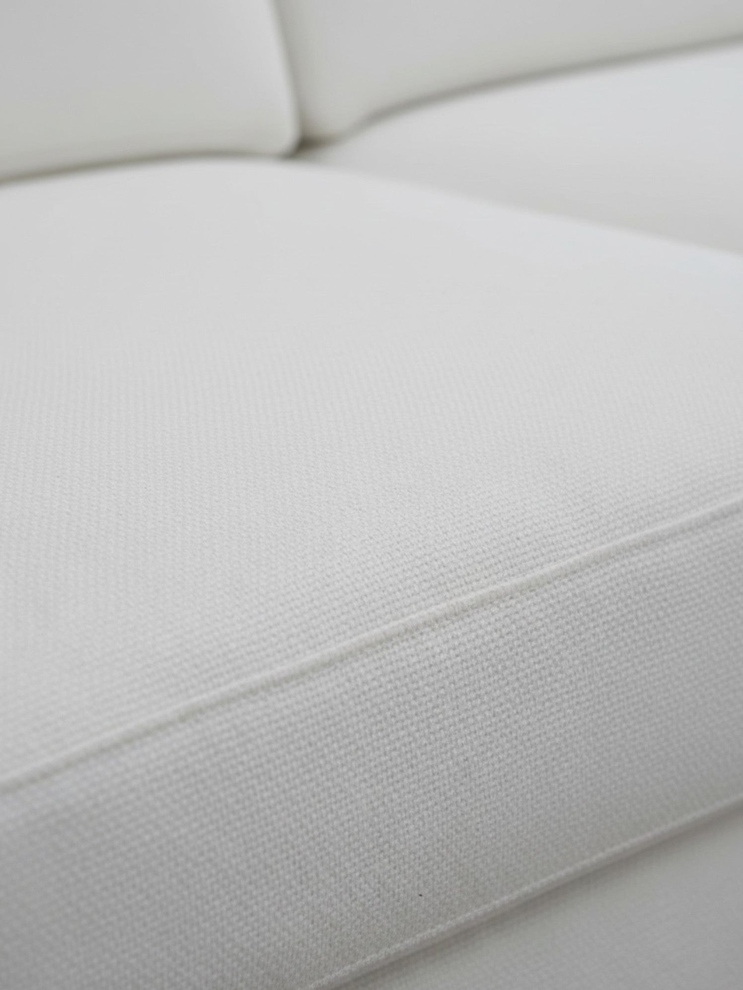 Gros plan sur le revêtement en chenille blanc du canapé Eira de TOCO Meubles, montrant la texture douce et détaillée.