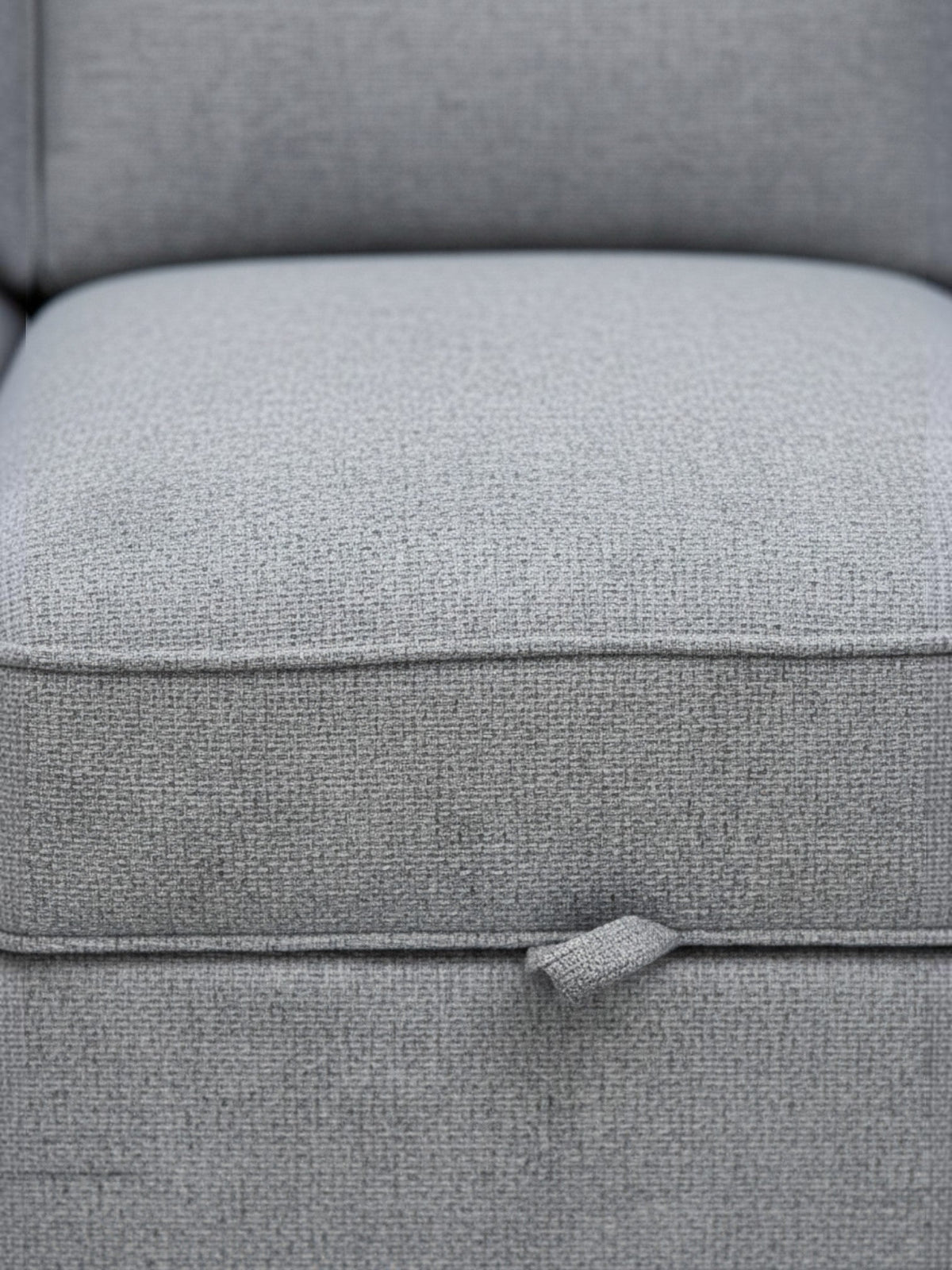 Gros plan sur le tissu gris texturé du canapé-lit Amani de TOCO Meubles avec sa languette de déploiement