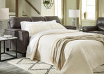 TOCO Meubles Canapé-lit Kairo marron en aspect cuir, convertible en lit, avec couette crème et jeté de lit beige.