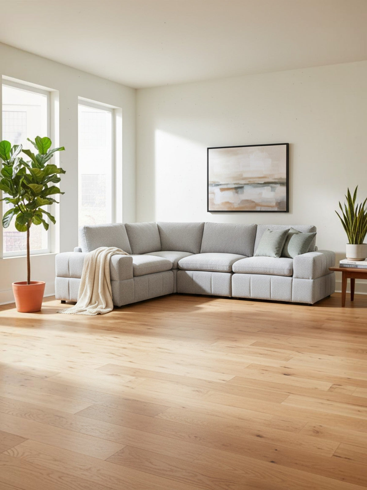 Canapé modulaire quatre pièces gris clair TOCO Meubles dans un salon lumineux avec parquet en bois et plante verte