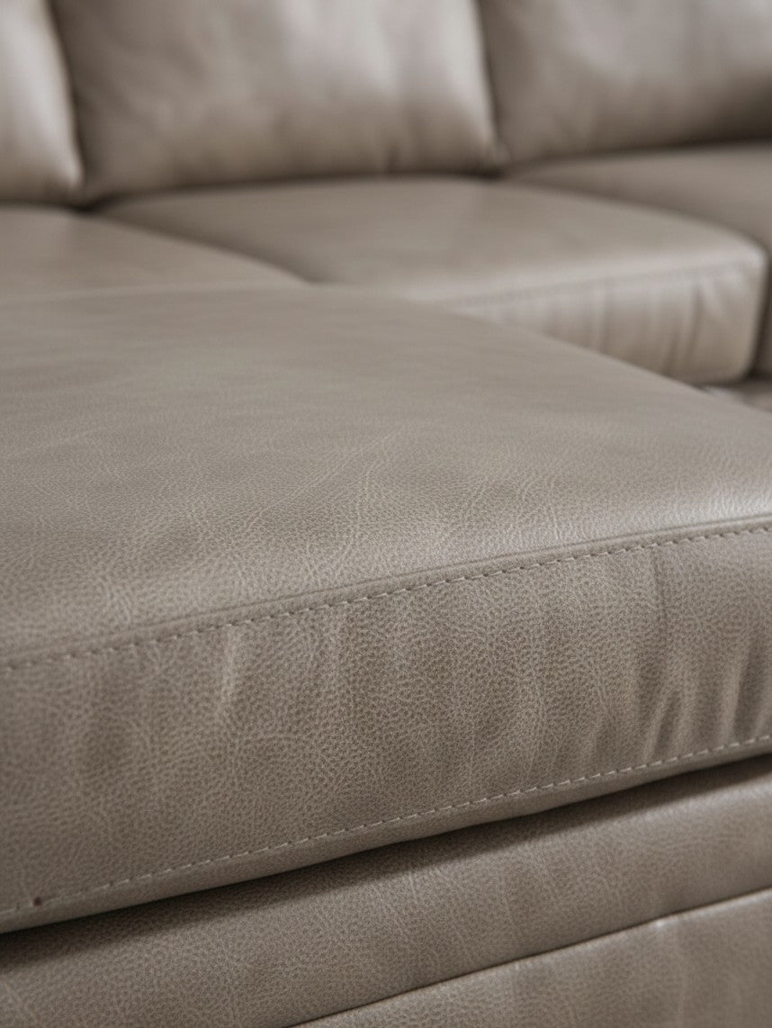 Gros plan sur le revêtement en cuir beige du canapé sectionnel Amuleto de TOCO Meubles avec coutures détaillées