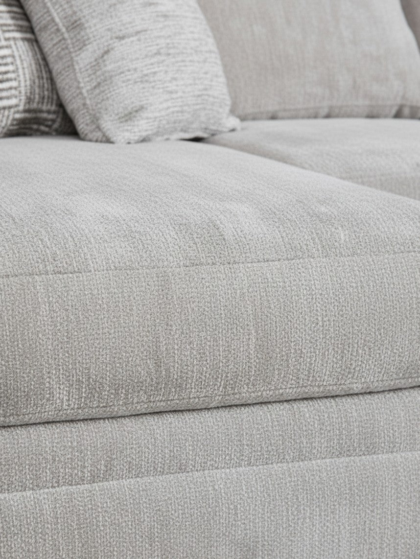 Gros plan sur le tissu texturé gris clair du canapé sectionnel Gaby de TOCO Meubles avec coussins décoratifs