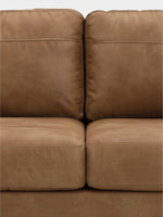 Gros plan sur les coussins en cuir caramel du canapé Telora de TOCO Meubles avec des coutures détaillées.