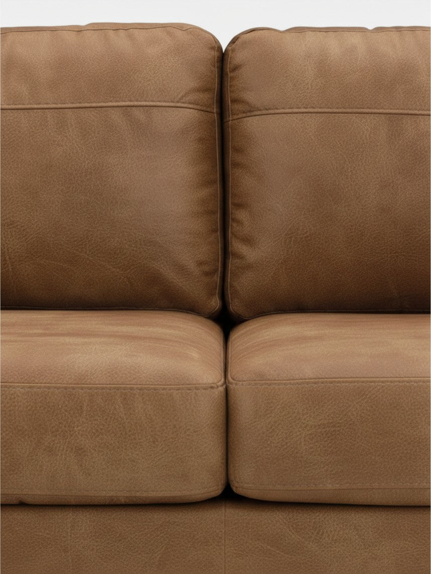 Gros plan sur les coussins en cuir caramel du canapé Telora de TOCO Meubles avec des coutures détaillées.