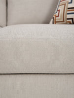 Gros plan sur le tissu beige texturé du canapé Toscana de TOCO Meubles avec un coussin à motifs géométriques
