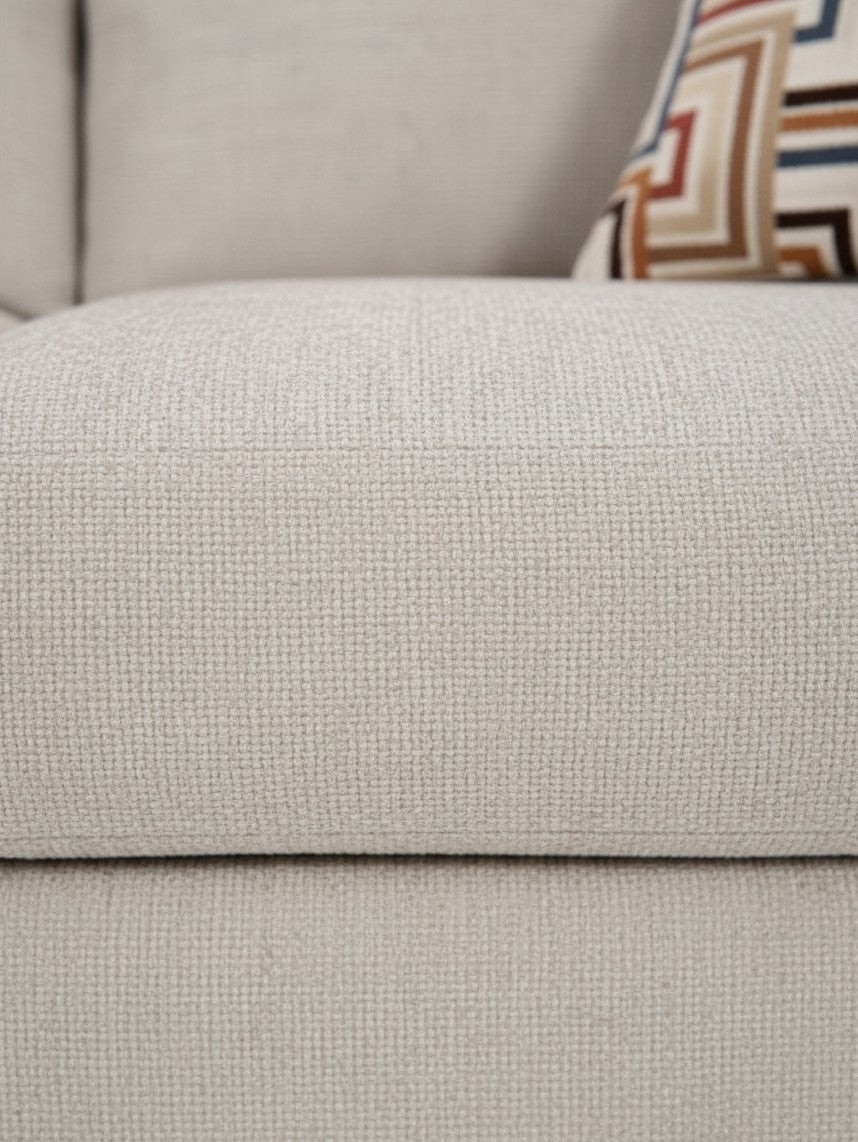 Gros plan sur le tissu beige texturé du canapé Toscana de TOCO Meubles avec un coussin à motifs géométriques