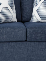 Causeuse Evan de TOCO Meubles en tissu bleu texturé avec deux coussins décoratifs à motifs géométriques blancs et bleus