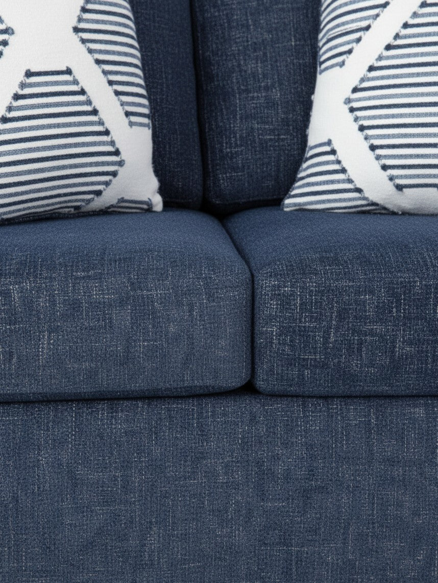 Causeuse Evan de TOCO Meubles en tissu bleu texturé avec deux coussins décoratifs à motifs géométriques blancs et bleus