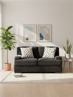 Causeuse Mistral TOCO Meubles en tissu noir texturé avec coussins décoratifs à motifs dans un salon lumineux