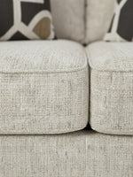 Gros plan sur le tissu texturé beige de la causeuse Moka de TOCO Meubles avec coussins décoratifs à motifs