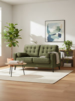 Causeuse TOCO Meubles Revo en tissu vert olive avec dossier capitonné dans un salon moderne et lumineux