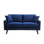Causeuse Royal bleue en velours de TOCO Meubles, avec coussins assortis et pieds en bois obliques.