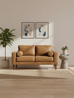 Causeuse Telora TOCO Meubles en cuir caramel avec coussins cylindriques dans un salon moderne et lumineux