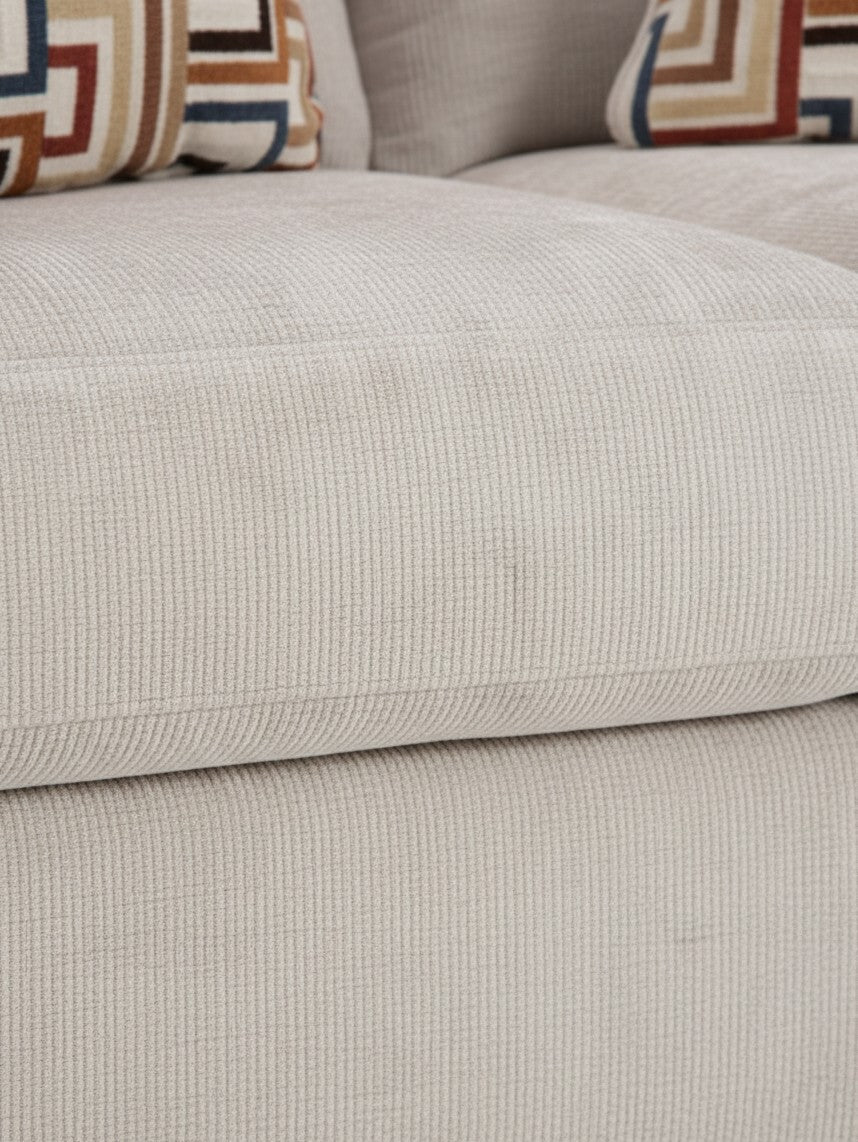 Gros plan sur le tissu en velours côtelé beige de la causeuse Toscana de TOCO Meubles avec coussins à motifs