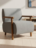 Chaise d'appoint Maureen TOCO Meubles en tissu gris avec accoudoirs et pieds en bois dans un salon contemporain