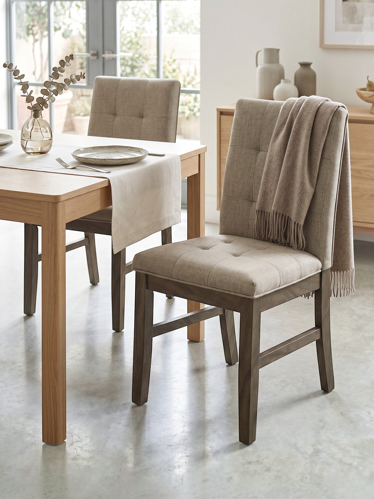 Chaise de cuisine TOCO Meubles Véronika en tissu brun capitonné avec structure en bois massif gris dans une salle à manger