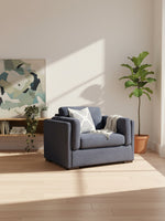 Chaise et demi TOCO Meubles Evan en tissu bleu marine avec coussin décoratif et jeté dans un salon ensoleillé