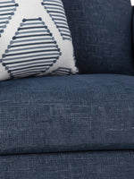 Gros plan sur le tissu bleu texturé de la chaise Evan de TOCO Meubles avec un coussin décoratif à motifs géométriques