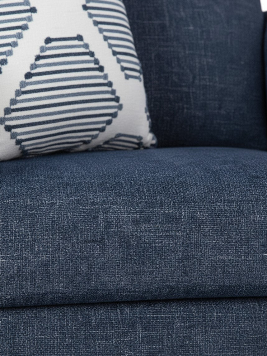 Gros plan sur le tissu bleu texturé de la chaise Evan de TOCO Meubles avec un coussin décoratif à motifs géométriques