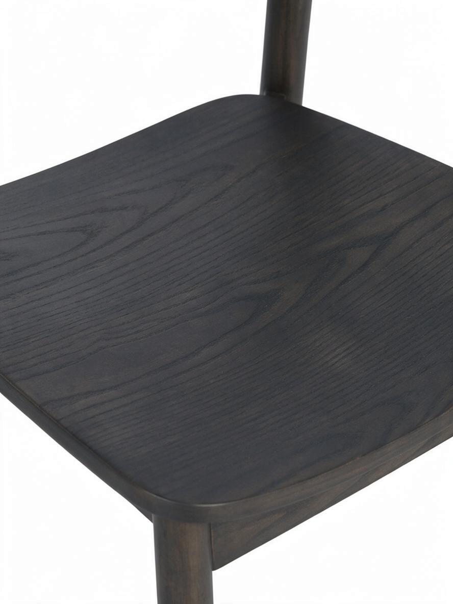 Gros plan sur l'assise en bois massif mocha de la chaise de salle à manger Jona par TOCO Meubles avec grain visible