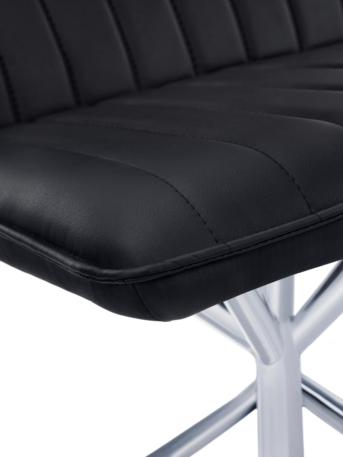 Gros plan sur le siège en similicuir noir capitonné de la chaise Marika de TOCO Meubles avec base en métal chromé
