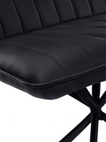 Gros plan sur le siège en similicuir noir capitonné de la chaise Marika de TOCO Meubles avec ses coutures verticales.