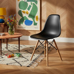 Chaise de salle à manger Zéphyr TOCO Meubles noire en plastique avec pieds en bois naturel et structure métallique noire.