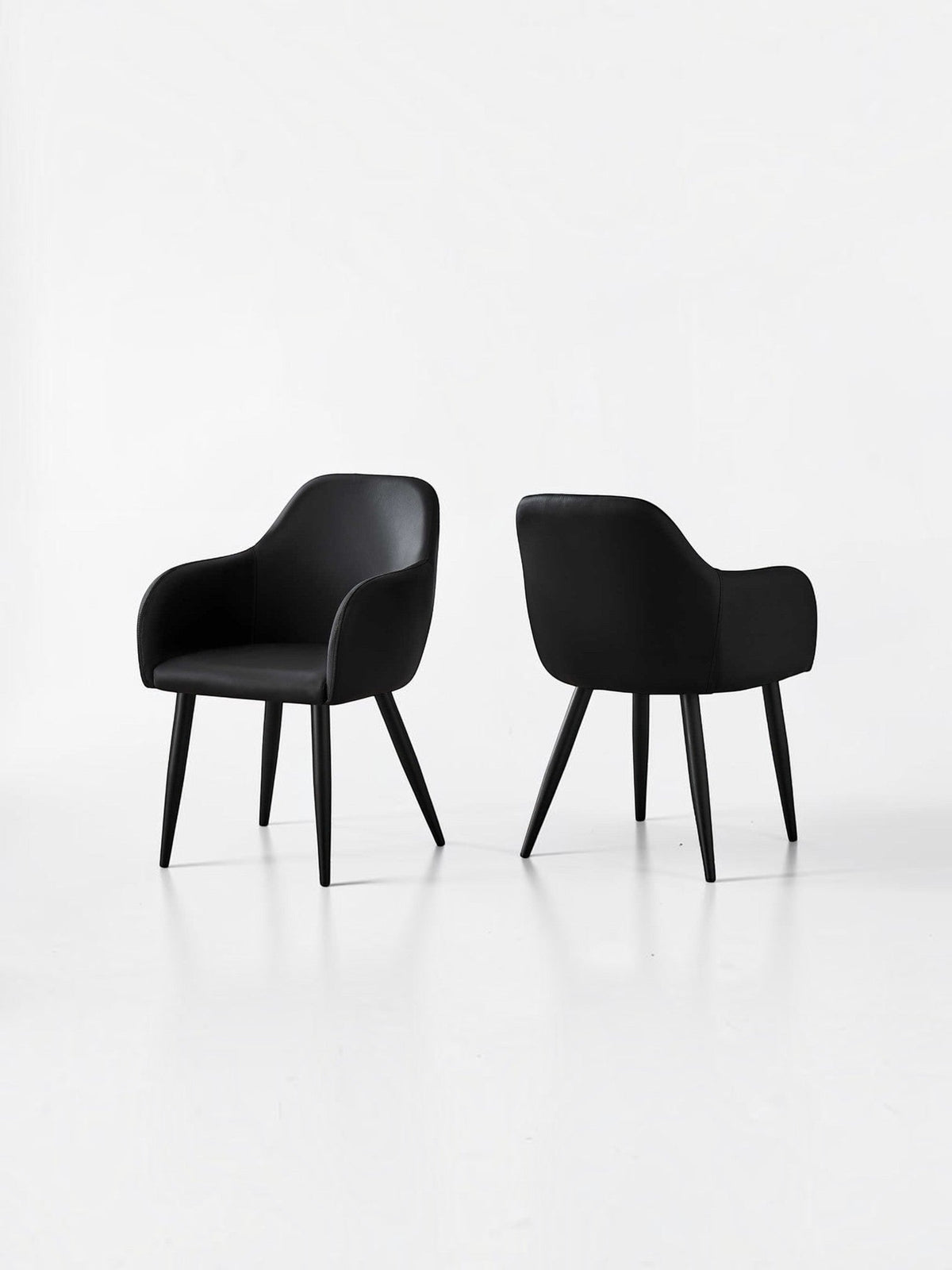 Chaise de salle à manger Parker en similicuir noir de TOCO Meubles, avec accoudoirs et pieds noirs, style contemporain.