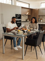 Couple prenant le petit-déjeuner sur des chaises de salle à manger Néo noires avec accoudoirs chez TOCO Meubles