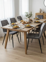 Chaise de salle à manger Élio par TOCO Meubles en velours gris avec pieds en métal noir autour d'une table en bois