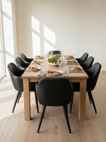 Chaise de salle à manger Parker TOCO Meubles en similicuir noir avec pieds en métal autour d'une table en bois clair