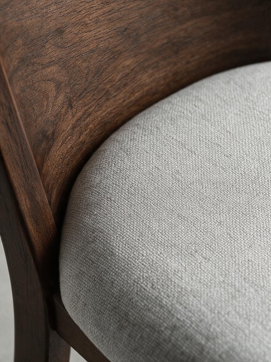 Gros plan sur le dossier en bois brun et le siège rembourré en tissu gris pâle de la chaise TOCO Meubles Tavio