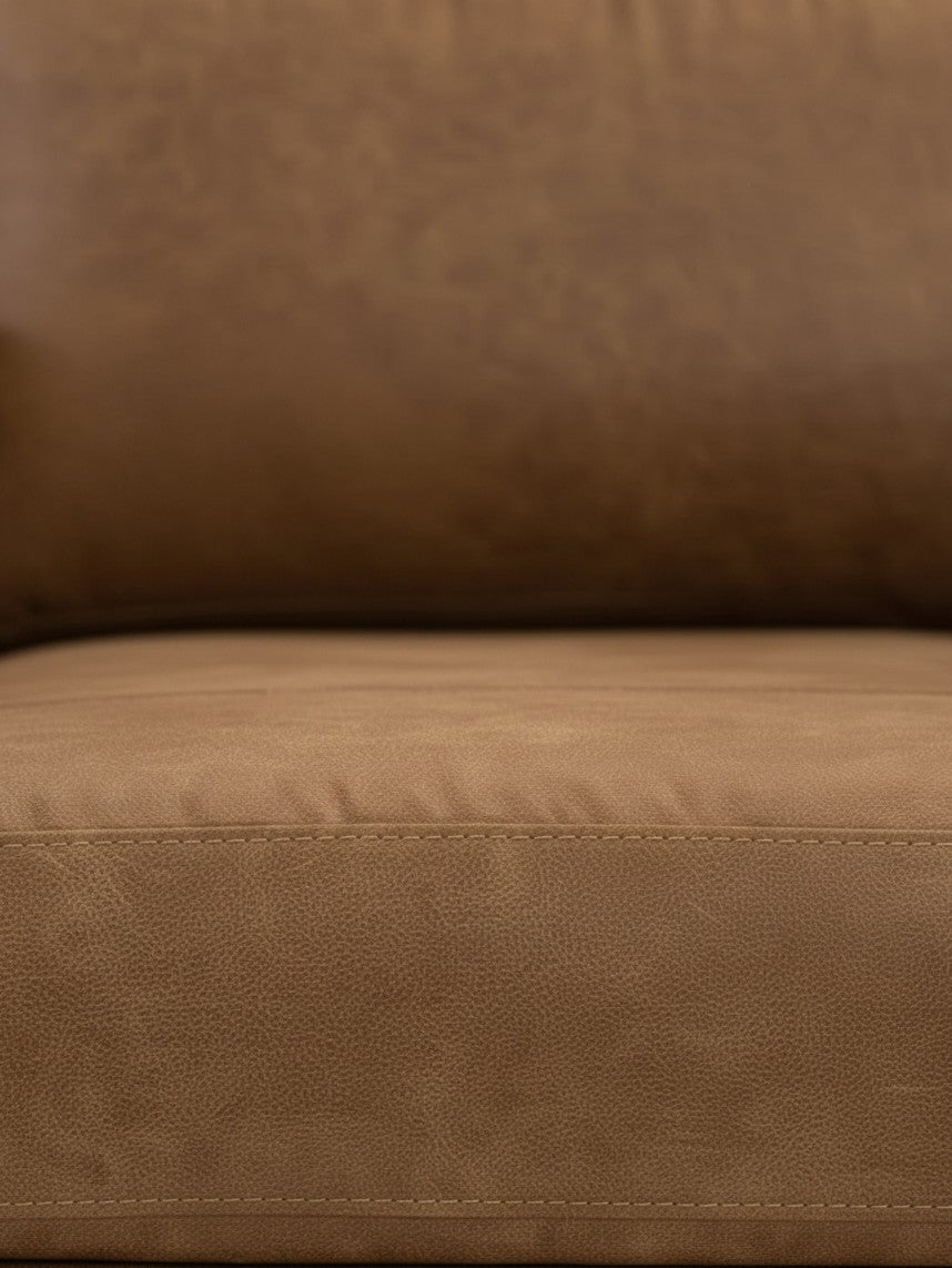Gros plan sur le revêtement en cuir synthétique caramel de la chaise Telora de TOCO Meubles avec coutures apparentes.