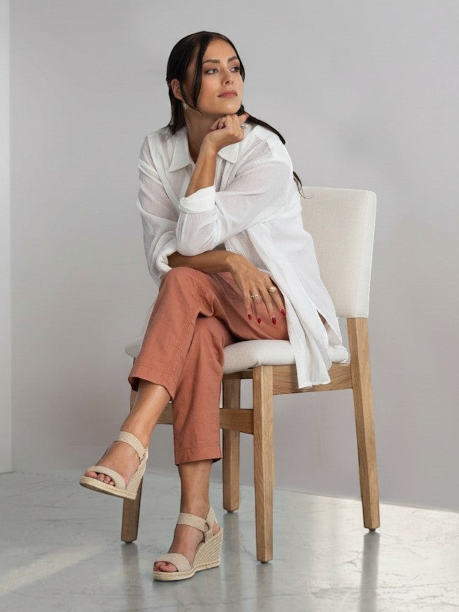 Femme assise sur une chaise TOCO Meubles en chêne scandinave avec assise rembourrée dans un intérieur minimaliste