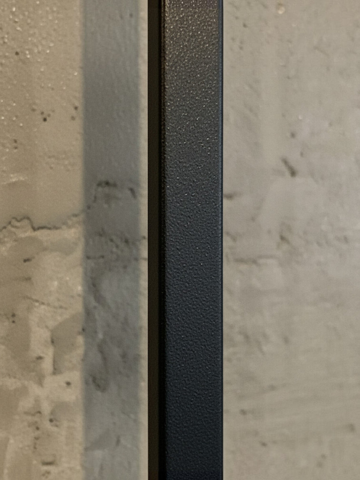 Détail de la texture en métal noir mat de la décoration murale Heather par TOCO Meubles sur fond texturé