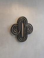 Décoration murale TOCO Meubles Aurum en métal noir avec un design géométrique abstrait et des courbes entrelacées.