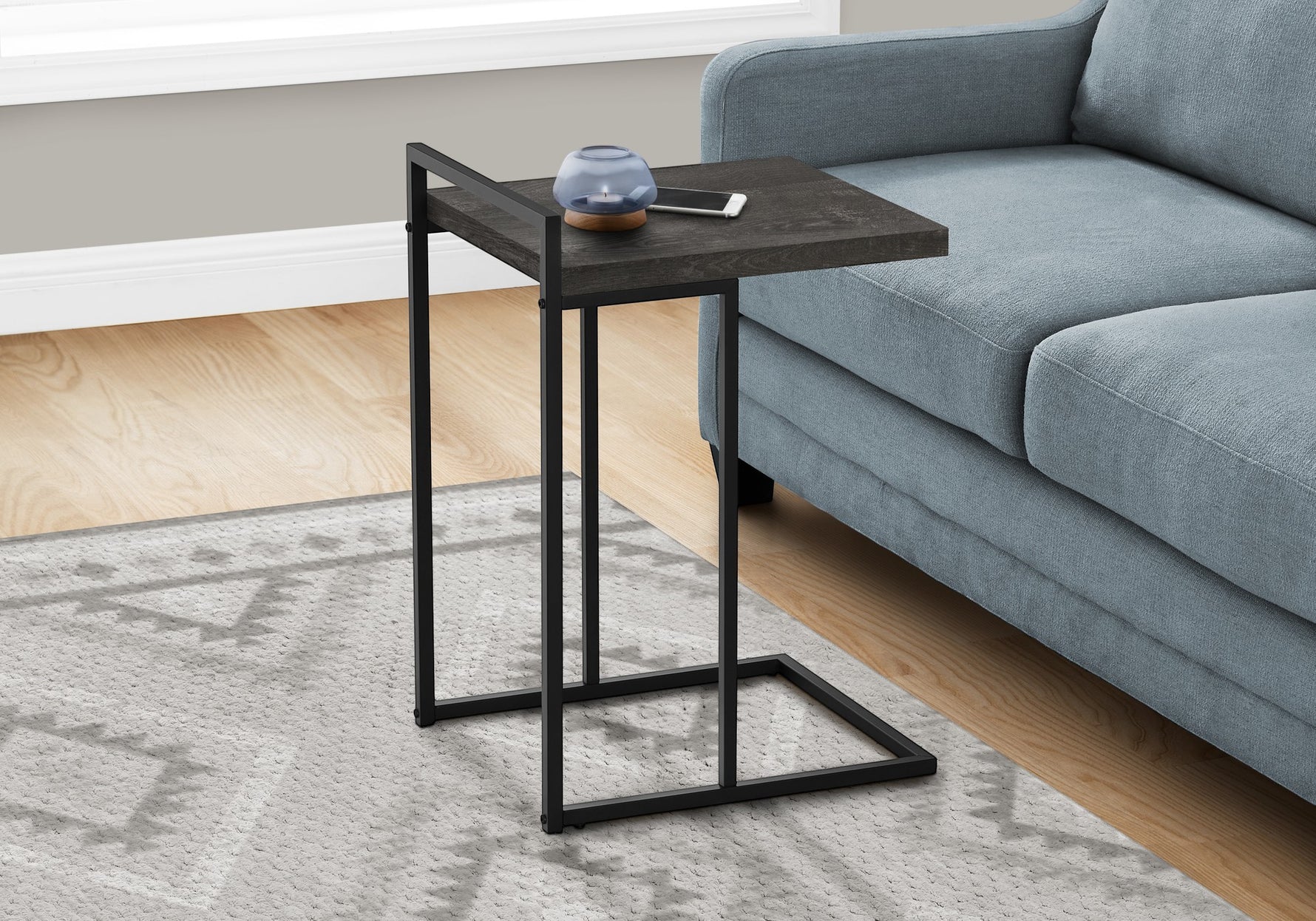 TOCO Meubles Eliott C-shaped side table with dark wood-effect top and black metal frame, next to a blue sofa.