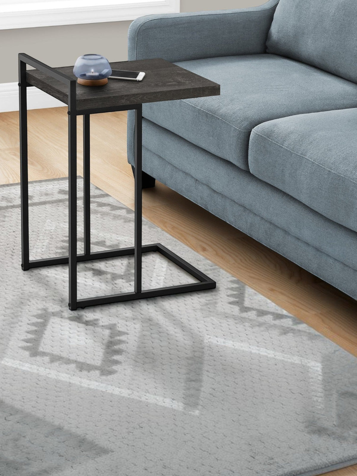 TOCO Meubles Eliott C-shaped side table with dark wood-effect top and black metal frame, next to a blue sofa.