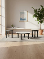 Ensemble de trois tables basses TOCO Meubles avec plateaux blancs et pieds noirs cylindriques dans un salon moderne