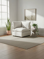 Fauteuil d'angle beige TOCO Meubles au design moderne et confortable dans un salon lumineux avec plante et tapis
