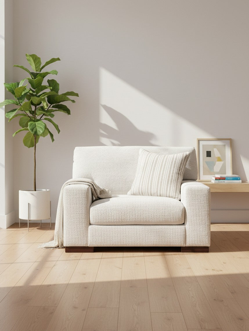 Fauteuil TOCO Meubles Figaro en tissu texturé blanc cassé avec coussin rayé et plaid dans un salon lumineux