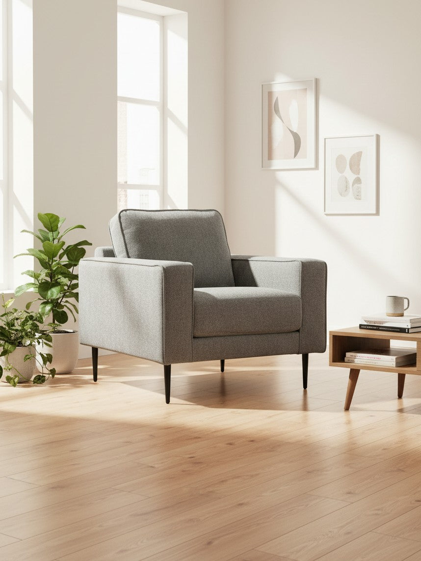 Fauteuil gris TOCO Meubles au design moderne avec pieds noirs fins dans un salon lumineux et épuré